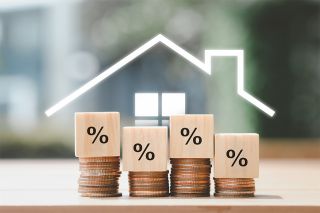 © tanoy1412 - stock.adobe.com Foto: Münzen und Holzwürfel mit Prozentzeichen
